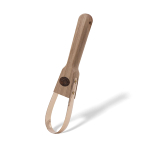 Kupferne Jähtschlinge mit Holzgriff, gebogener Kelle und logoähnlicher Verzierung, in minimalistischer Anordnung mit Schatten.