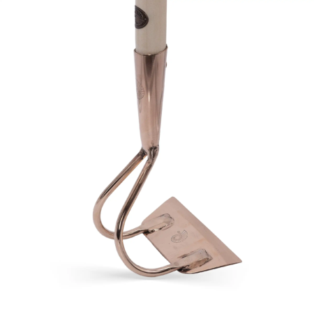 Kupferne Ziehhaue mit einem hellen Holzgriff, geformt für effektives Gartenarbeiten. Glänzende Oberfläche und präzise Kante.