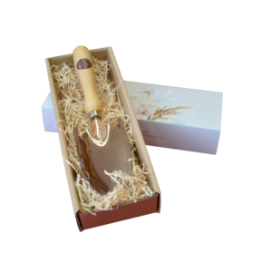Klein handlicher Blumenspaten in einer Geschenkbox mit Holzgriff und glänzender Kupferklinge, umgeben von Holzwolle.