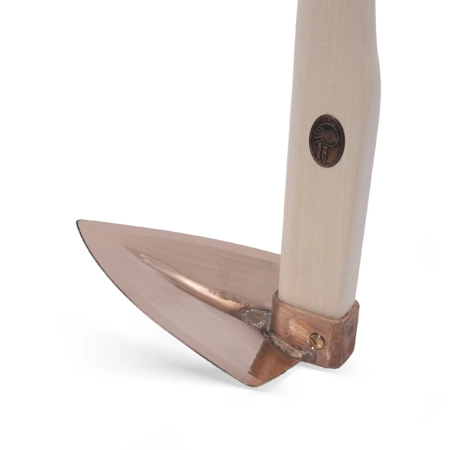 Kupferne Feldhaue mit einem hellen Holzgriff und einer stabilen, glänzenden Klinge. Detailaufnahme des Werkzeuges.